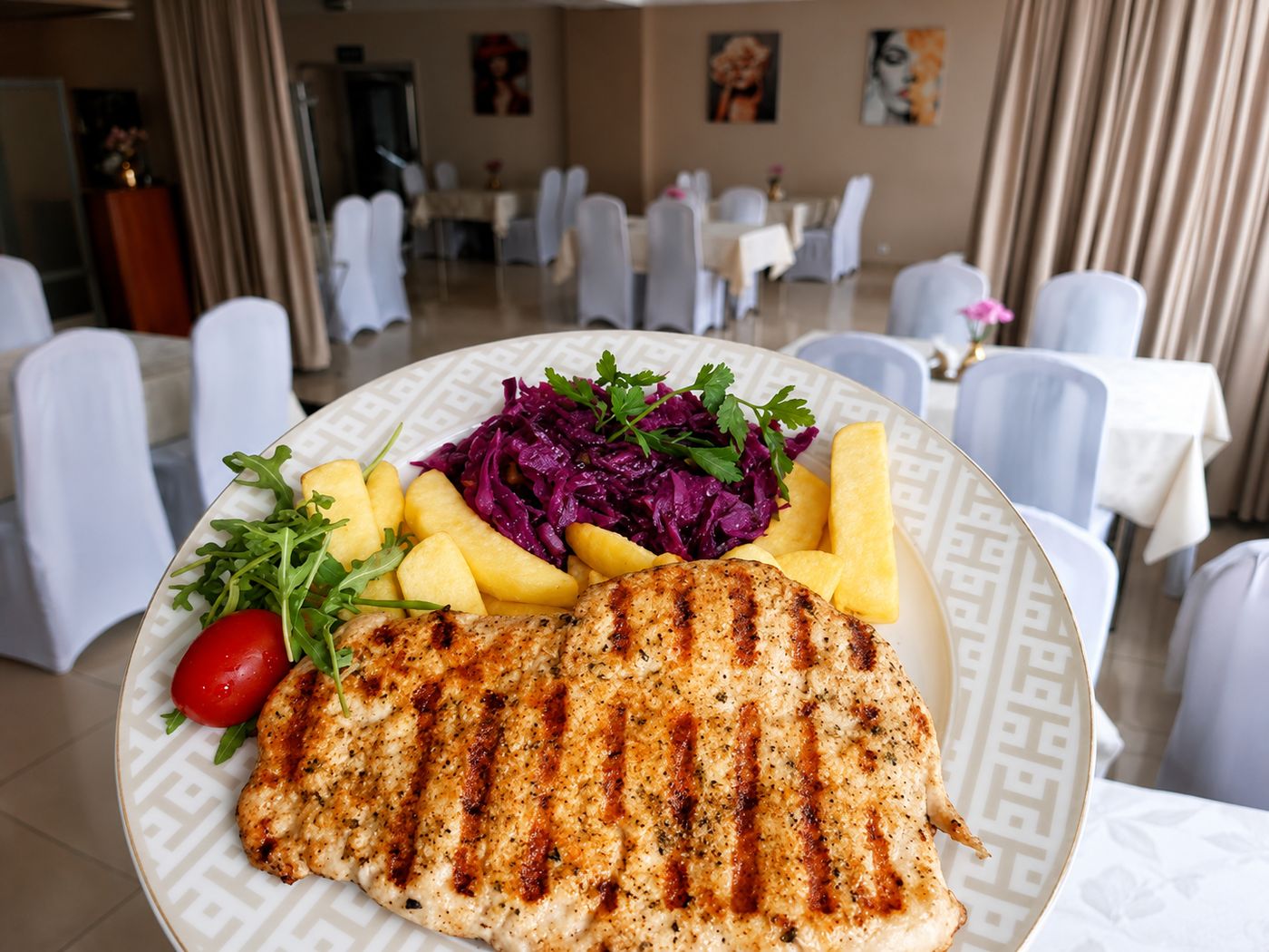 Grillowana pierś z kurczaka z ziemniakami i surówkami na tle sali restauracyjnej